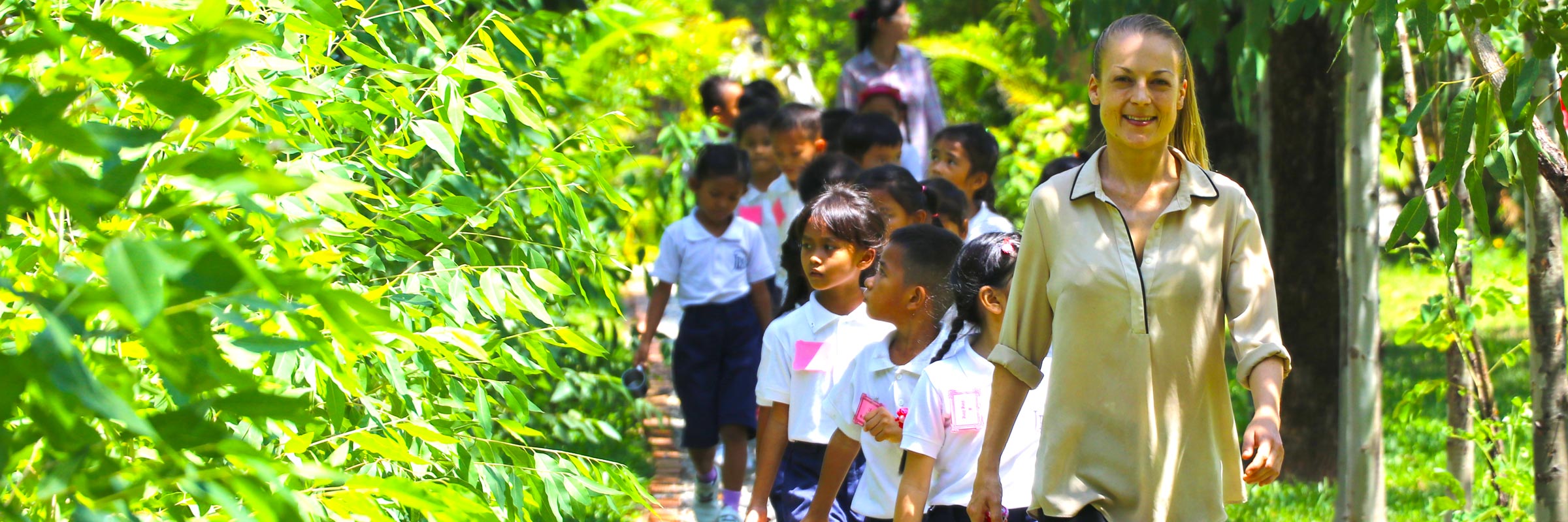 JPA teacher leading Grade 1 back to class after a physical education (PE) class. Jay Pritzker Academy, Siem Reap, Cambodia. Jay-Pritzker-Academy-Siem-Reap-Cambodia.
